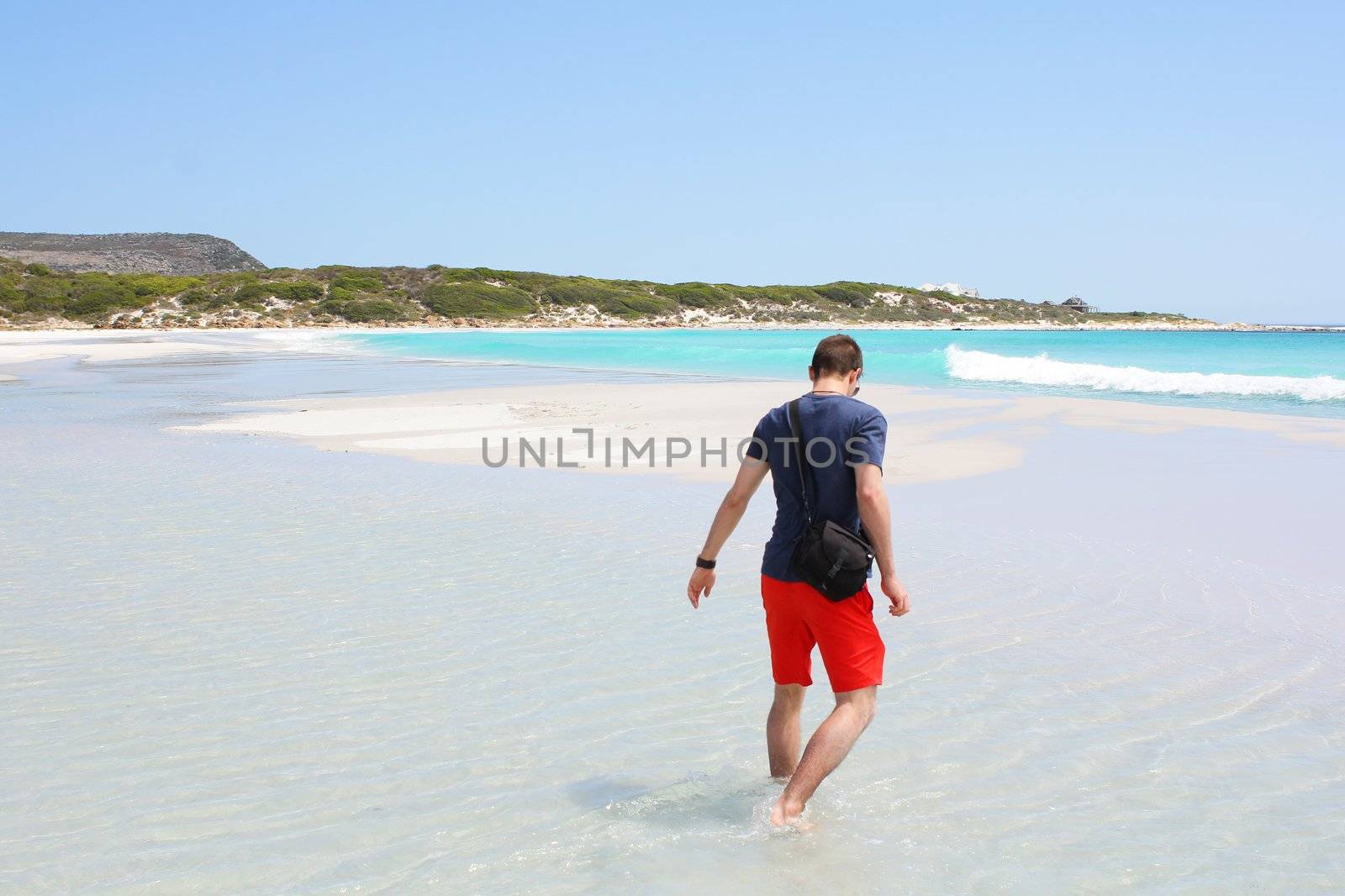 Man walking through water at Kommetjie Beach, Cape Town, South Africa