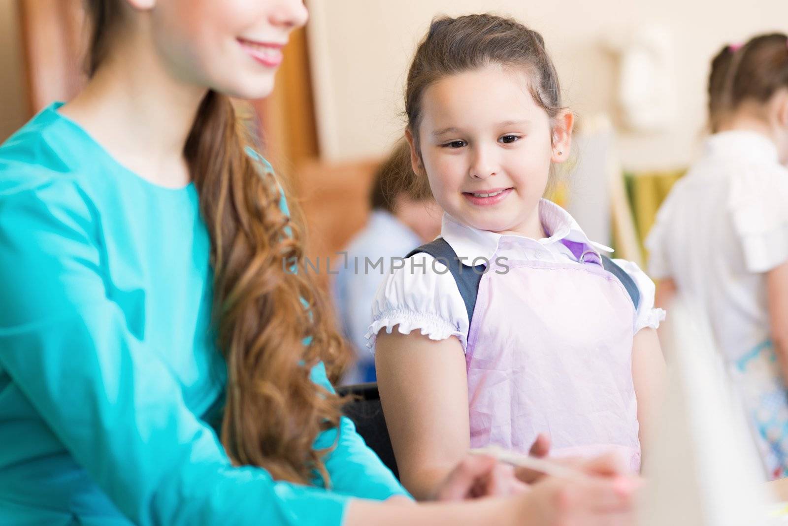 girl interested in drawing the teacher in the background paint other children