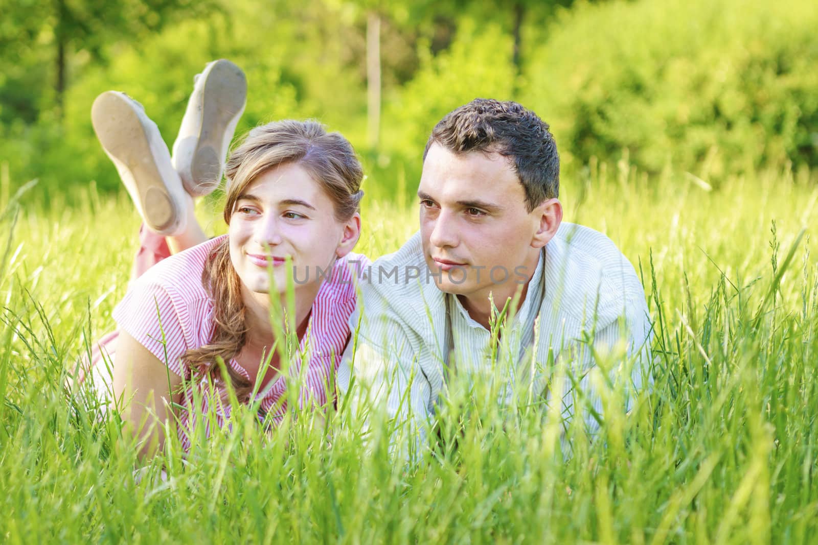 Young couple lying in park by manaemedia