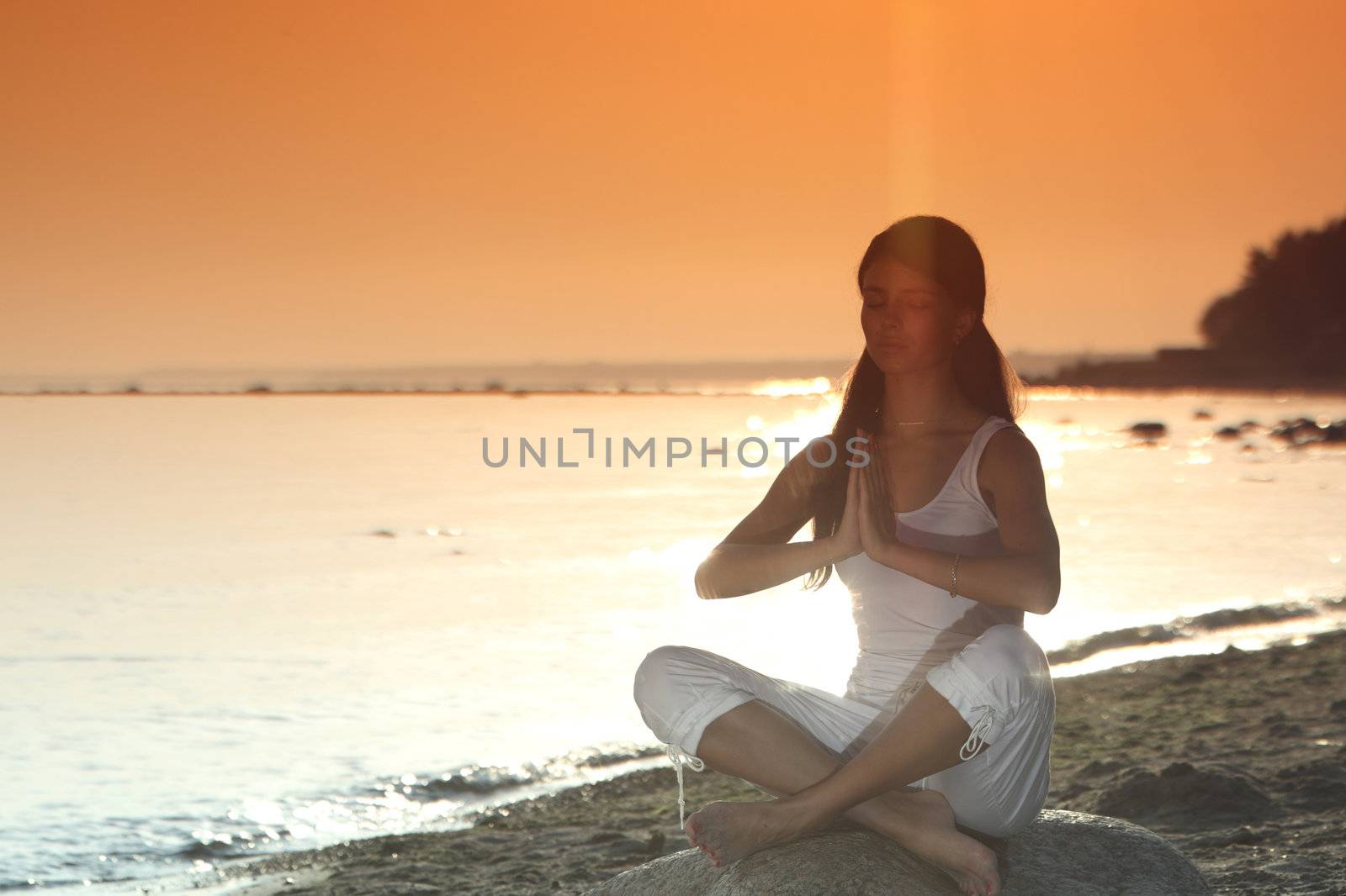 Young woman practicing yoga  near the ocean