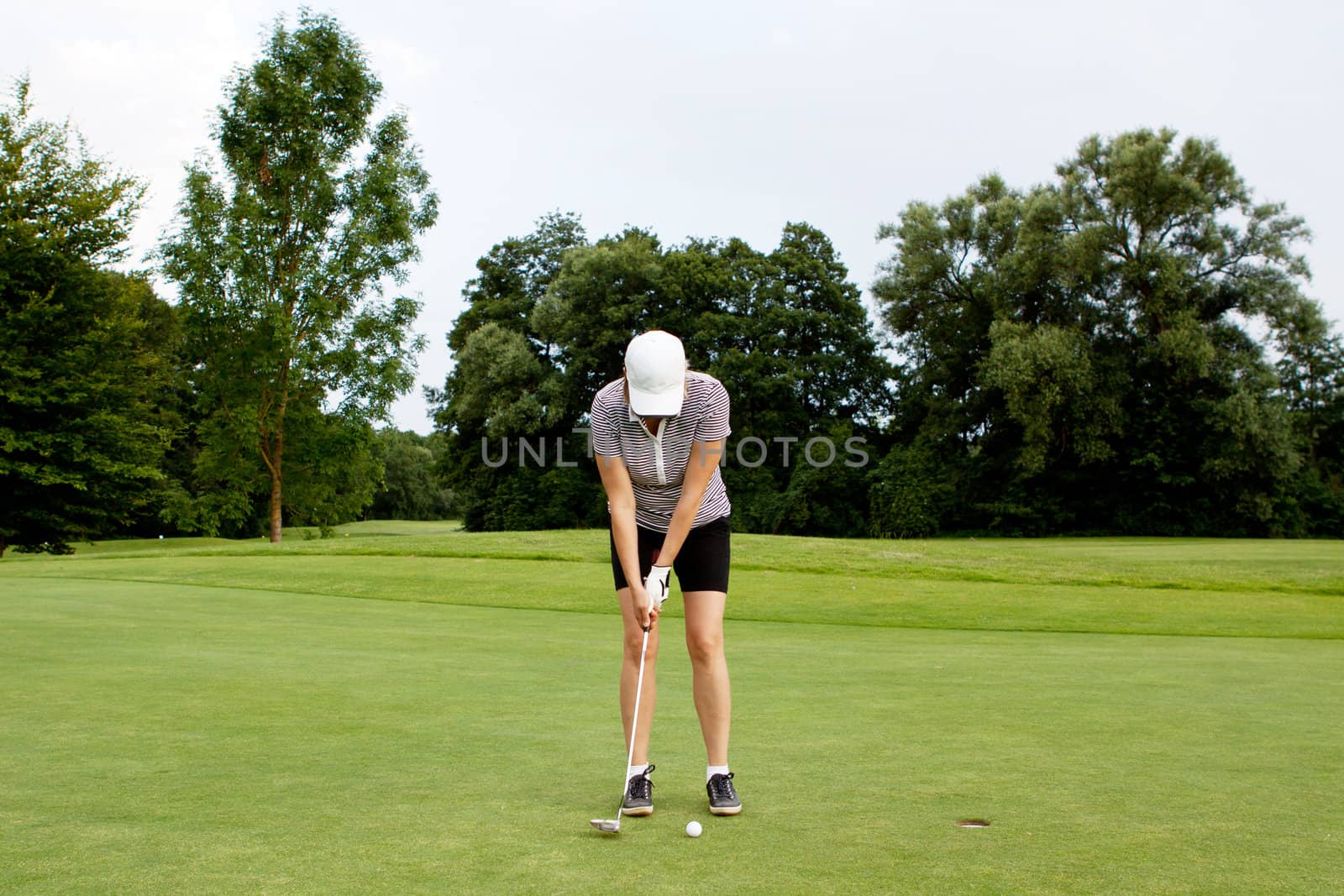 woman is playing golf on course  in summer in a golf-club