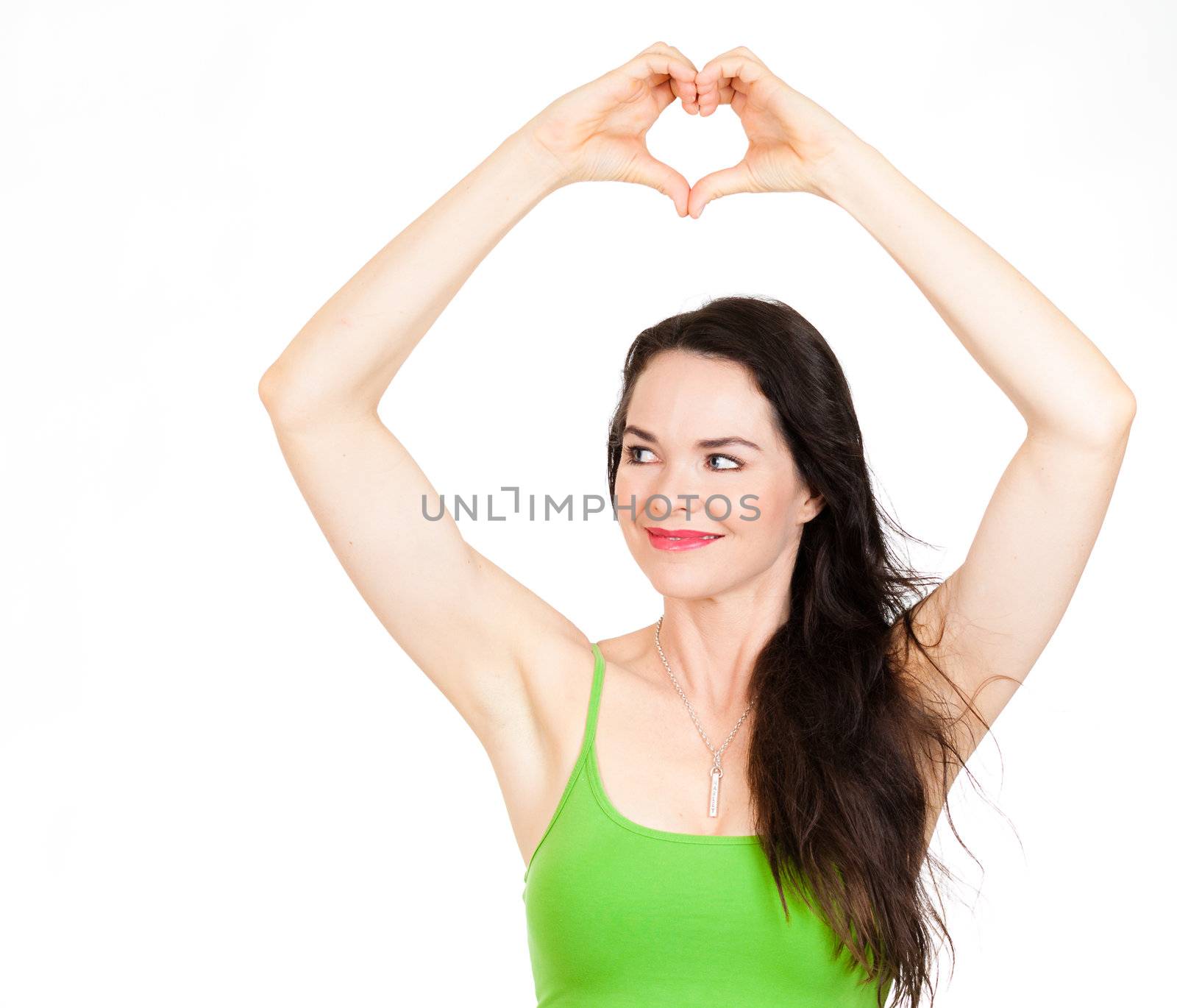 A beautiful young woman forming a love heart with her hands over her head and looks at copyspace. Isolated on white