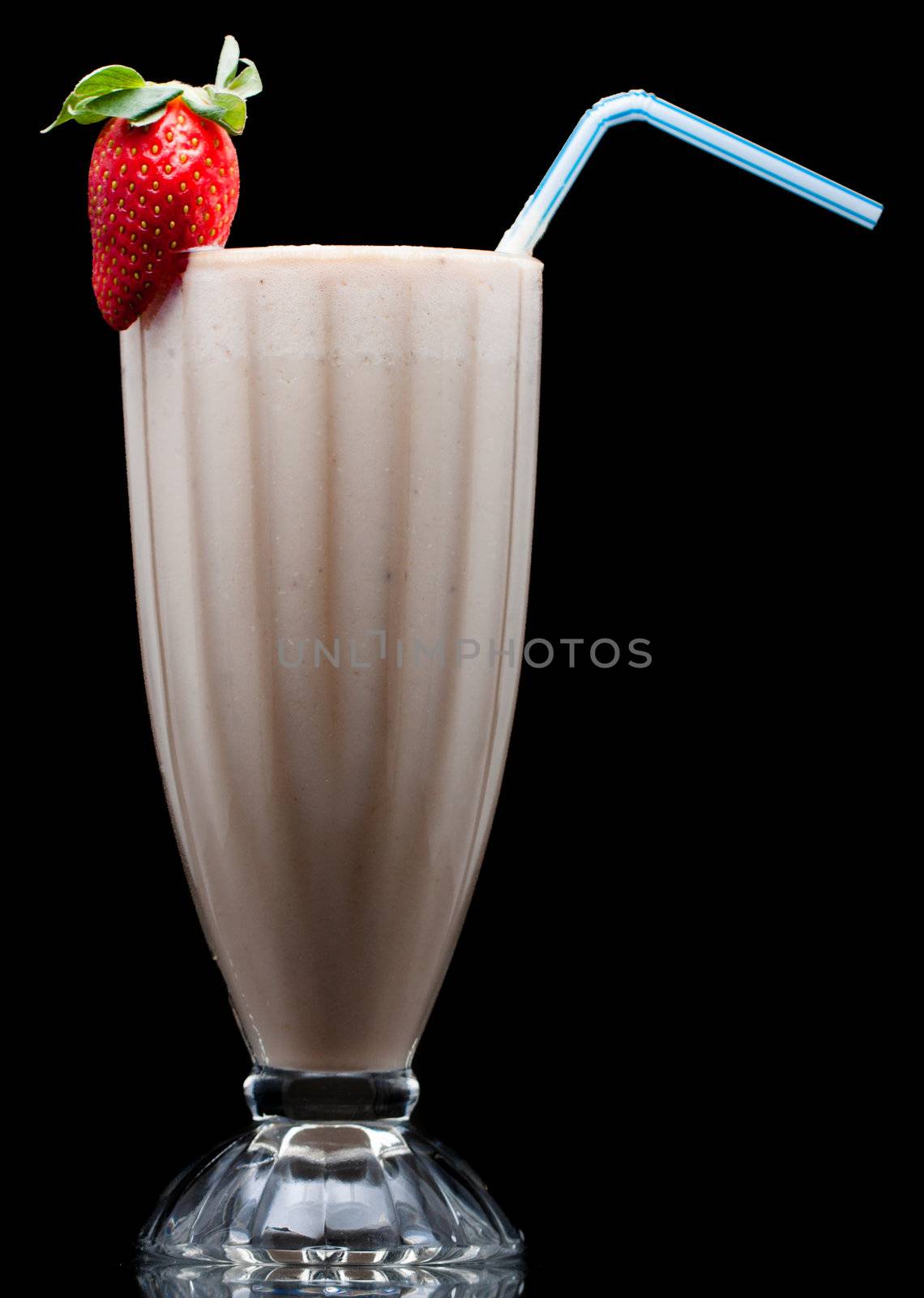 A delicious cold fruit smoothie or milk shake decorated with strawberry. Isolated on black