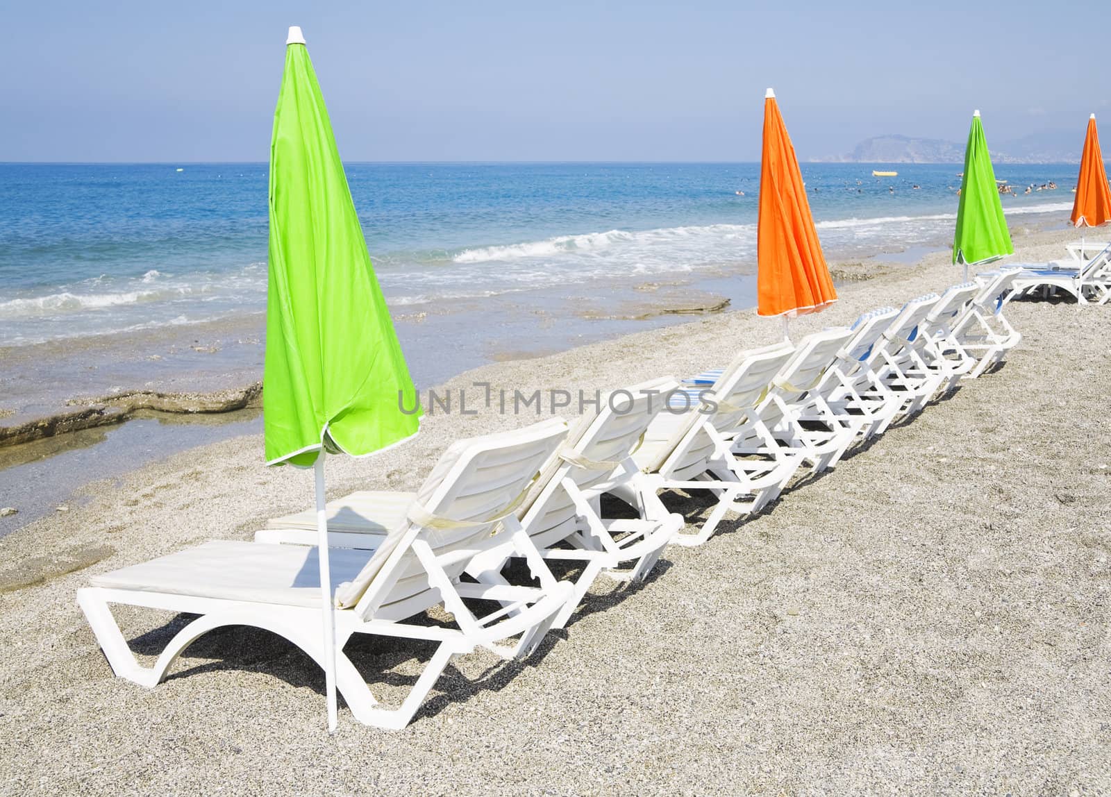Beach chair and colorful umbrella on the beach by Serp