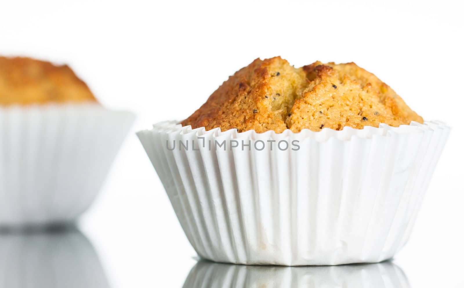 Close-up of a freshly home baked banana muffin on a reflective surface. Isolated on white.