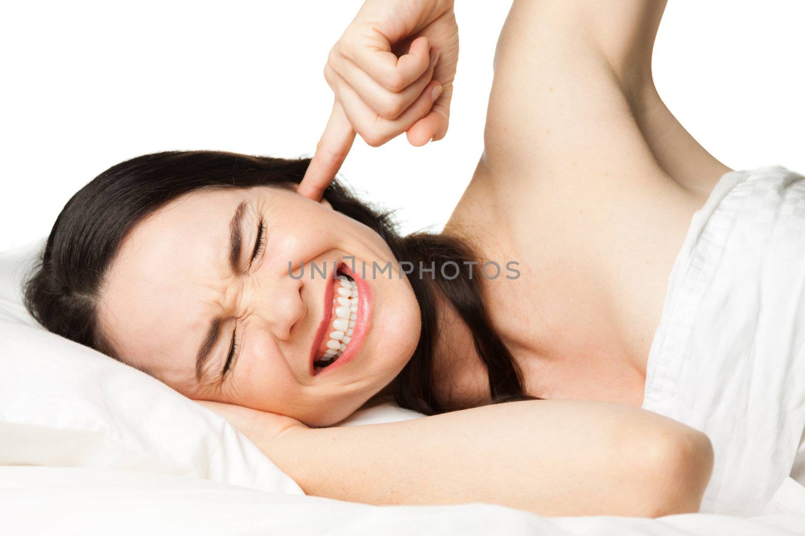 A tired, frustrated, sleepless, pretty woman putting her finger in her ear to block out disturbing noises.  Isolated over white