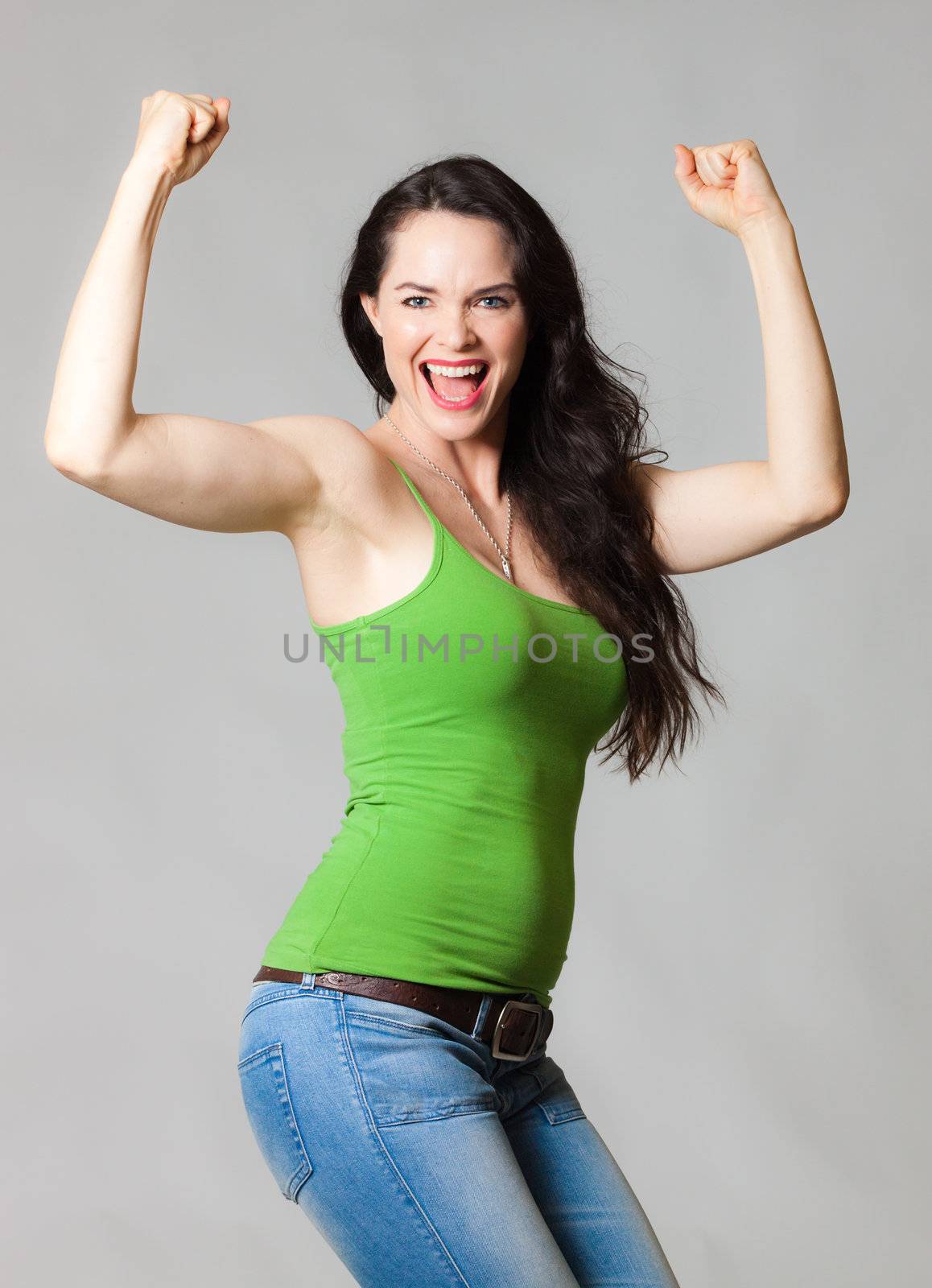 A happy cheerful young fit woman flexing her muscles