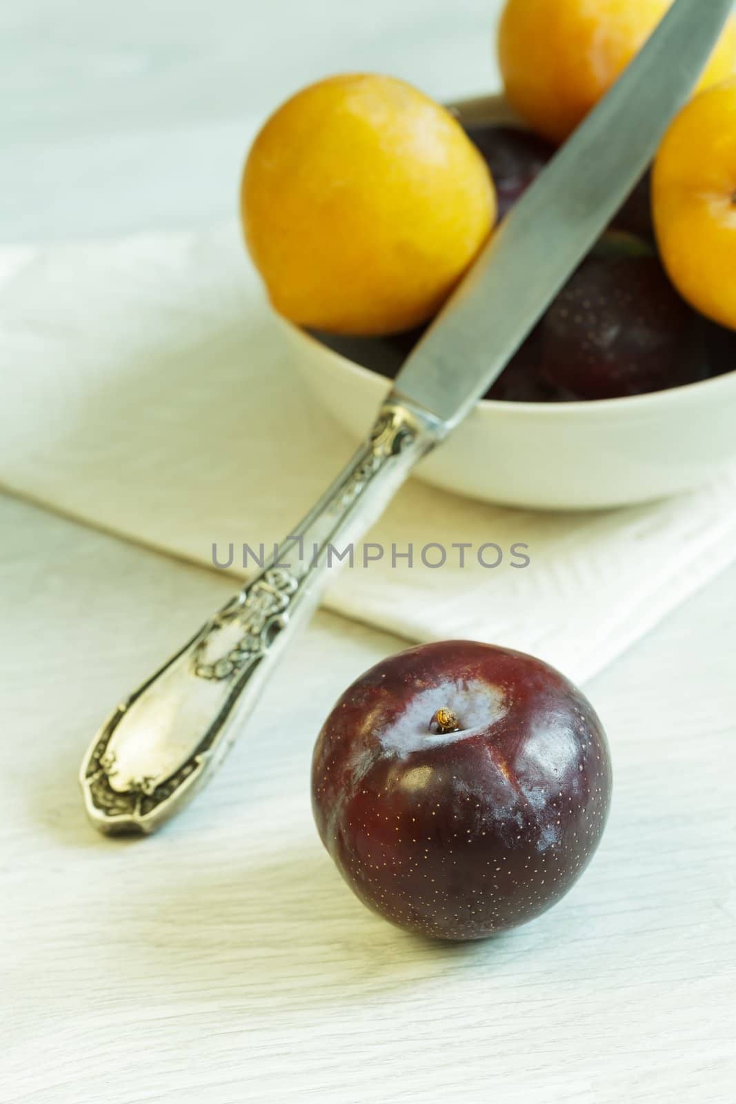 Purple plum and bowl with plums at the background