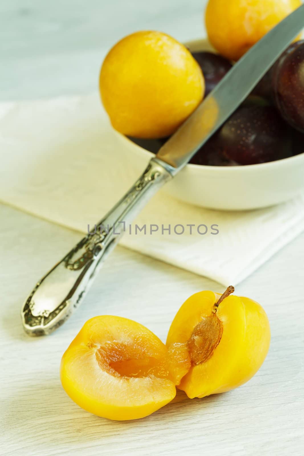 Cuted yellow plum and bowl with plums at the background