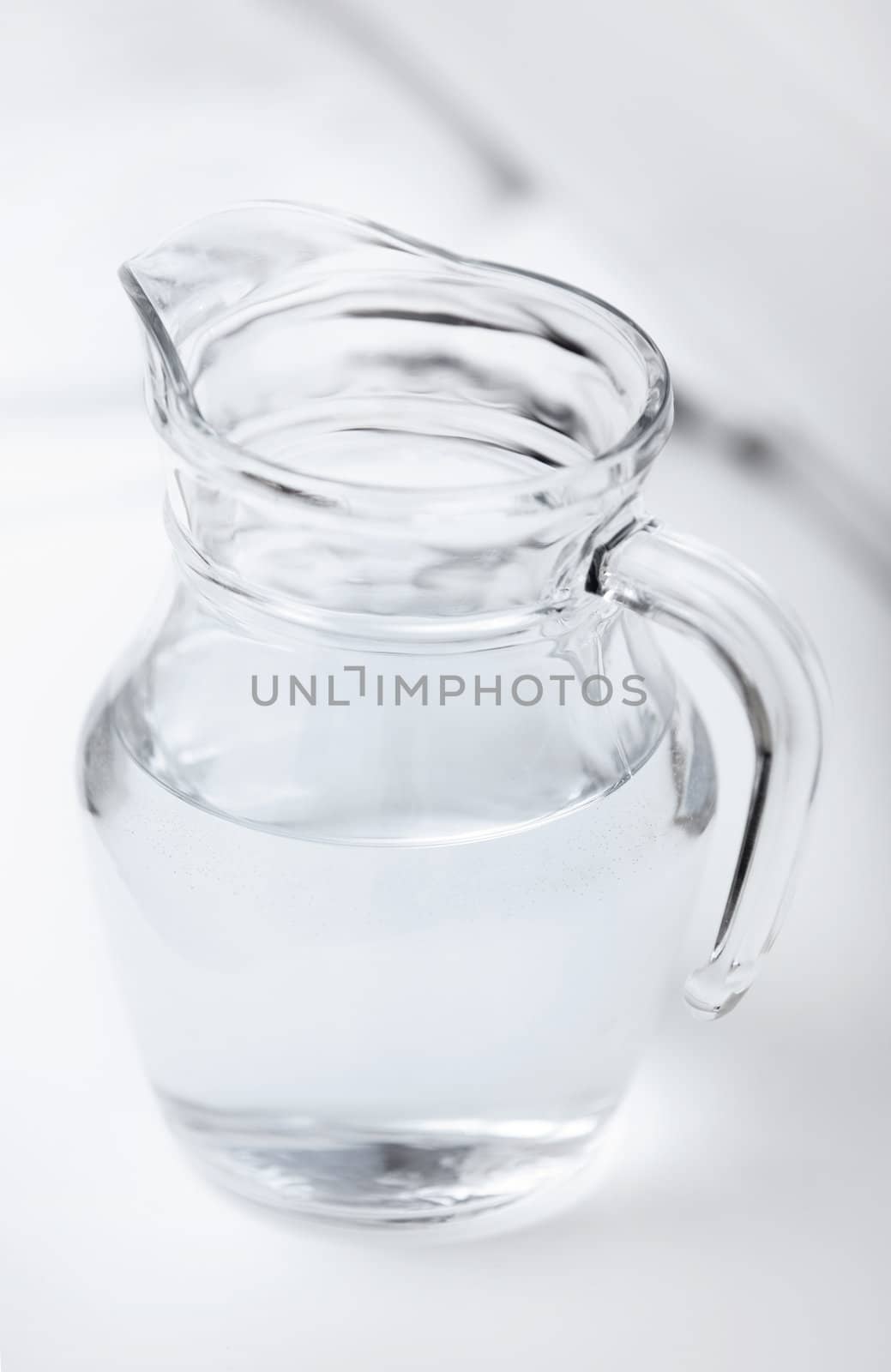 Transparent glass can with water on a table with shadows