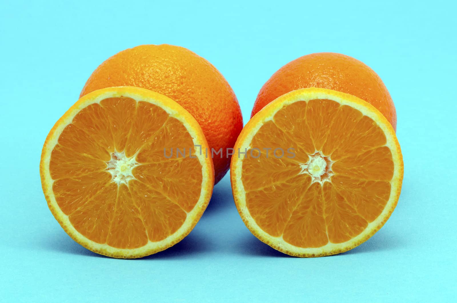 Oranges fruits full and sectioned on blue background. Healthy eating organic food items.