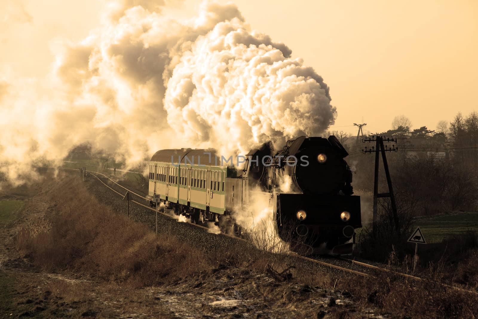 Vintage steam train passing through countryside, wintertime
