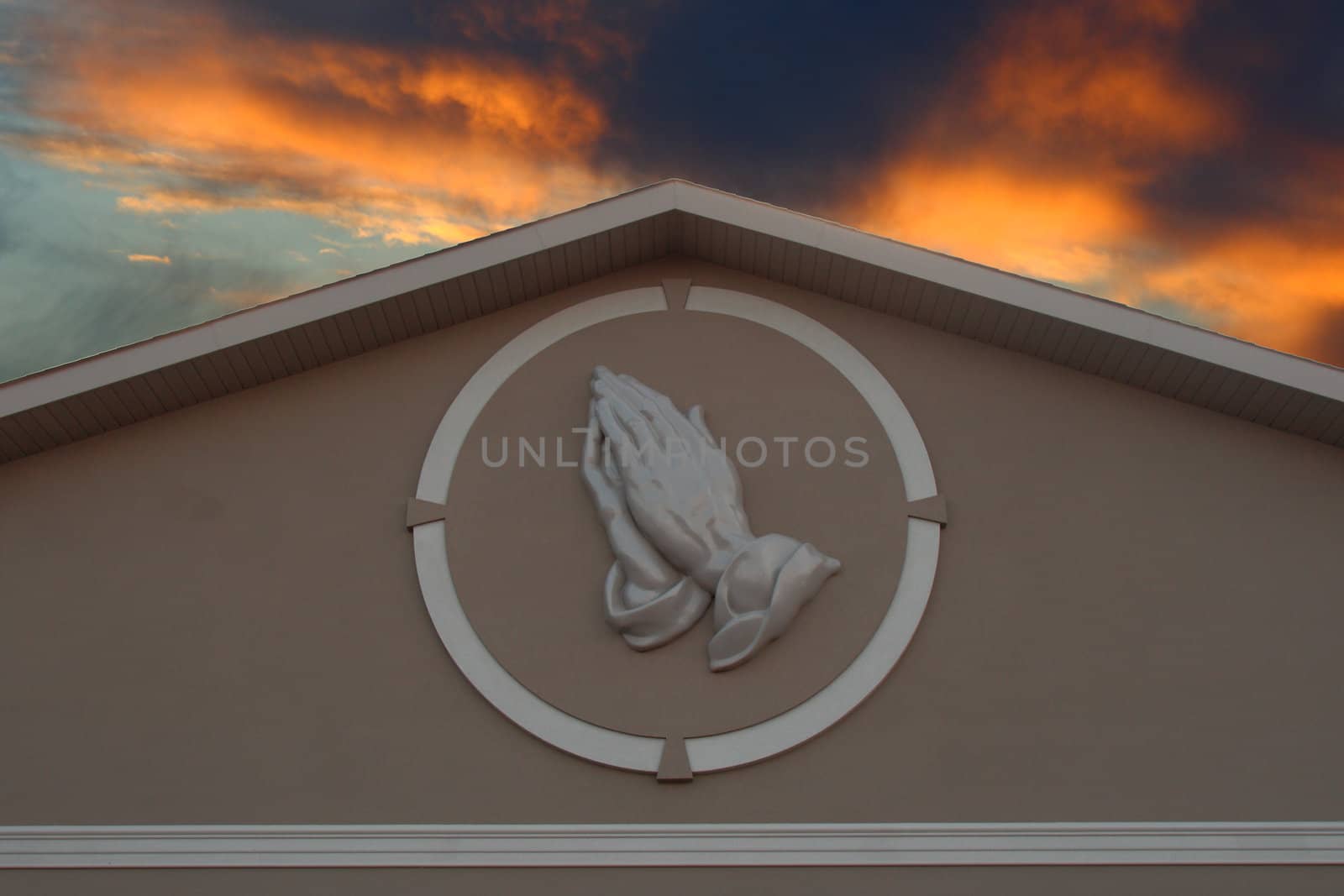 prayer hands against sunset sky