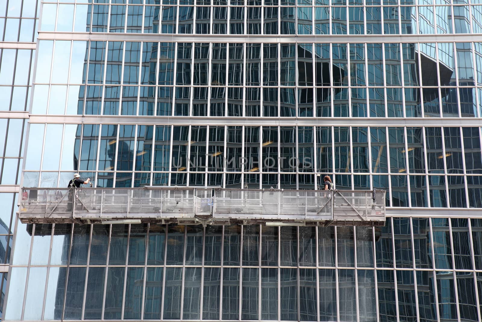 window washer cleaning windows on a modern highrise office tower building in the city