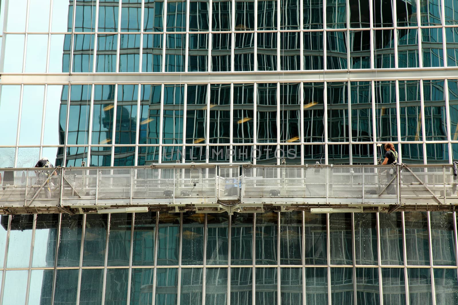 window washer cleaning windows on a modern highrise office tower building in the city