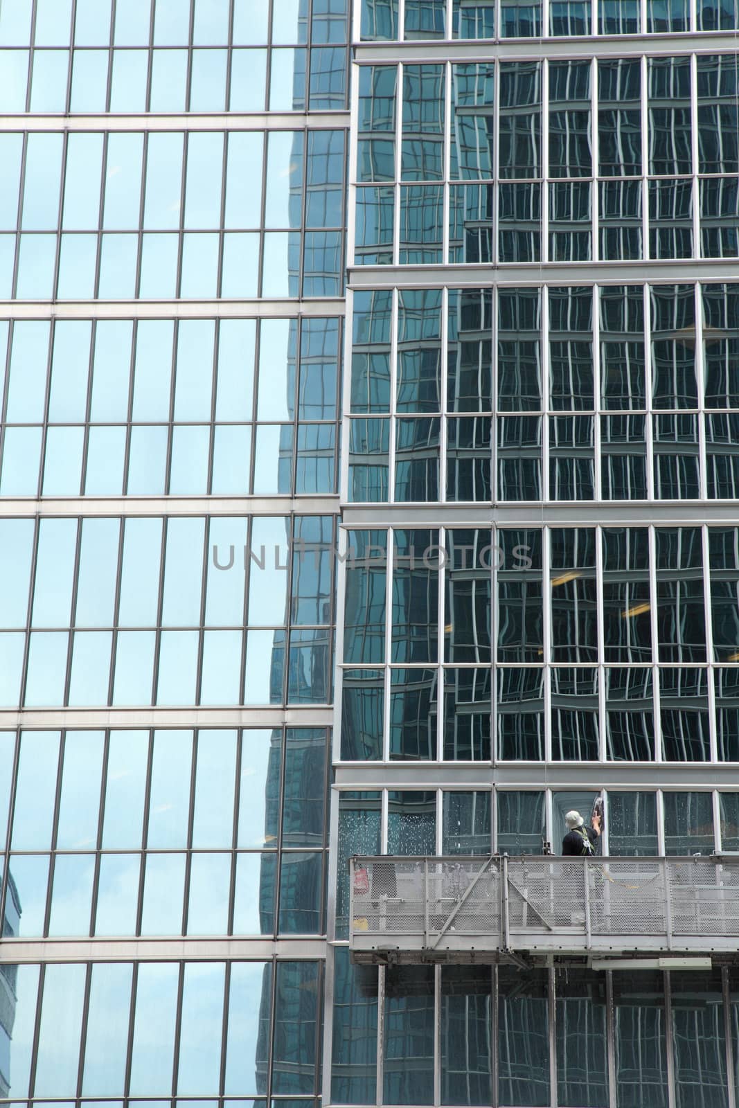 window washer cleaning windows on a modern highrise office tower building in the city