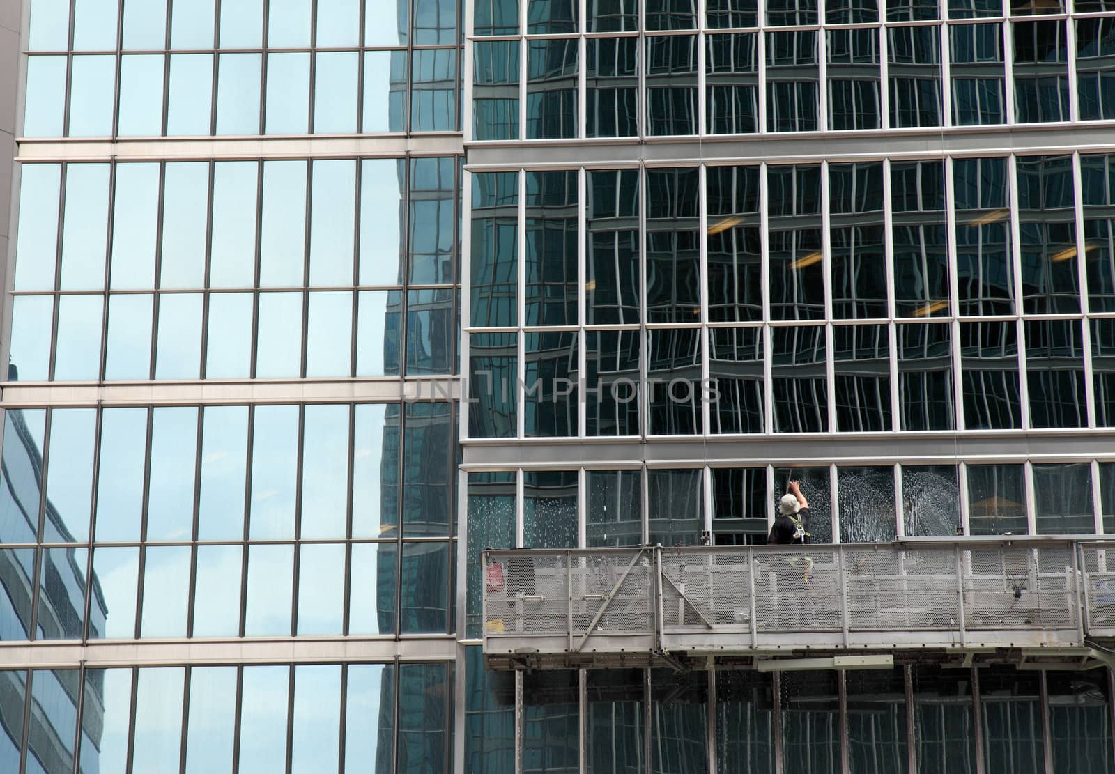 window washer cleaning windows on a modern highrise office tower building in the city