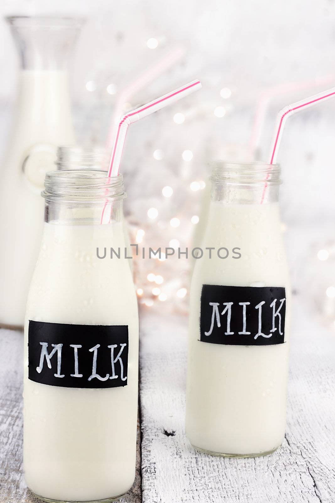 Glass bottles of milk with straws and antique milk bottle in background. Shallow depth of field. 