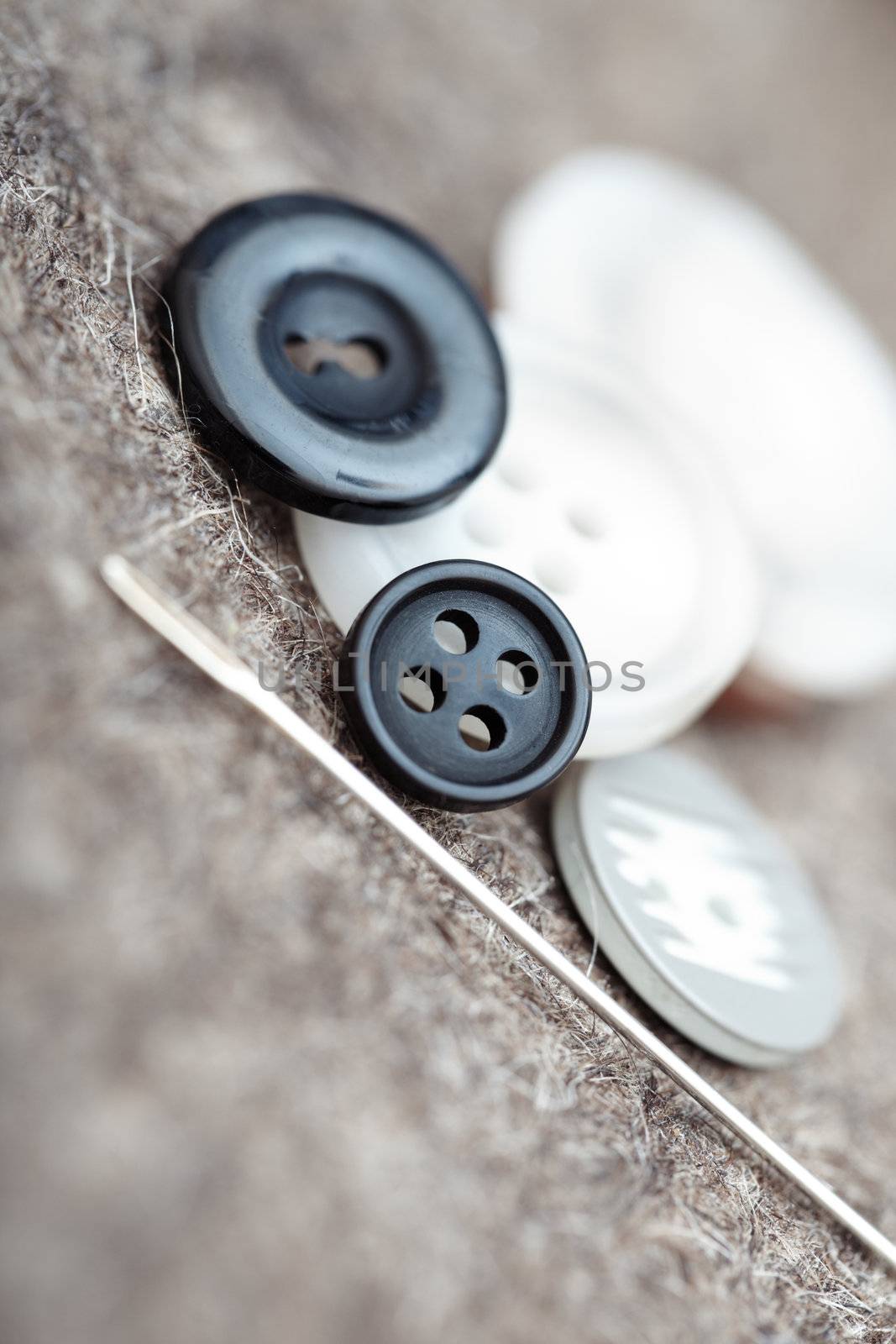 Buttons and sewing needle. Extremely close-up photo with shallow depth of field