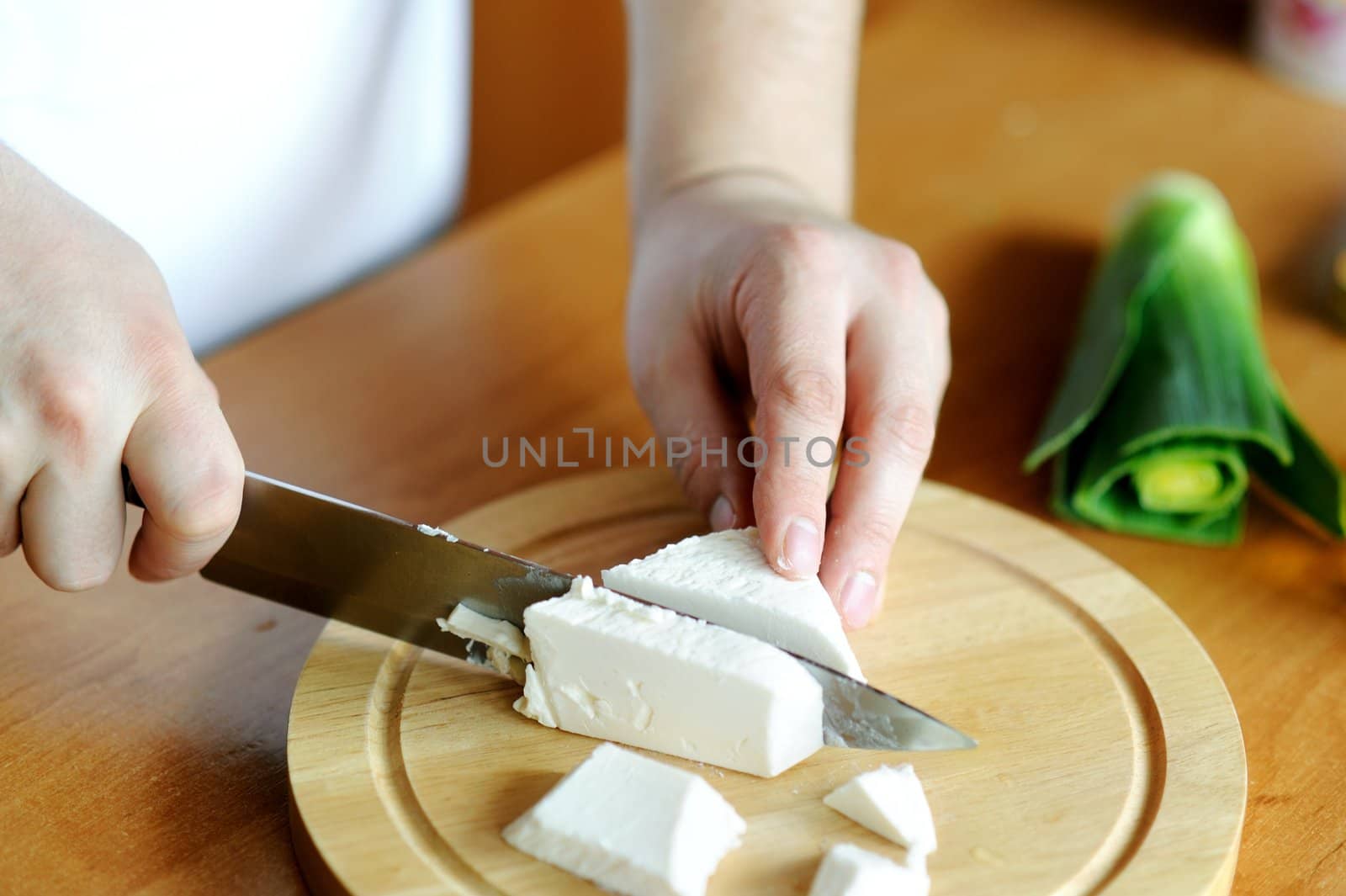 An image of hands cutting cheese on the board