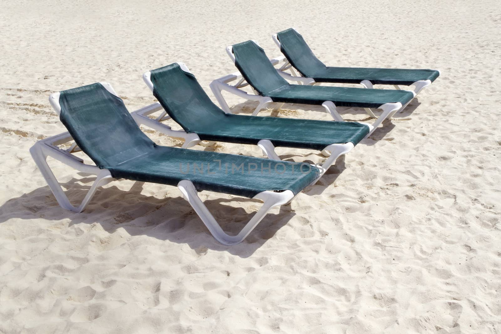 Rows of several green lounge chairs on the beach