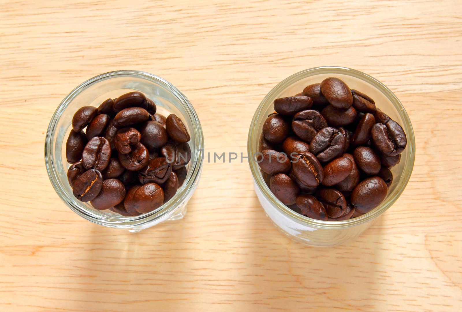 Coffee beans in glasses on wooden background