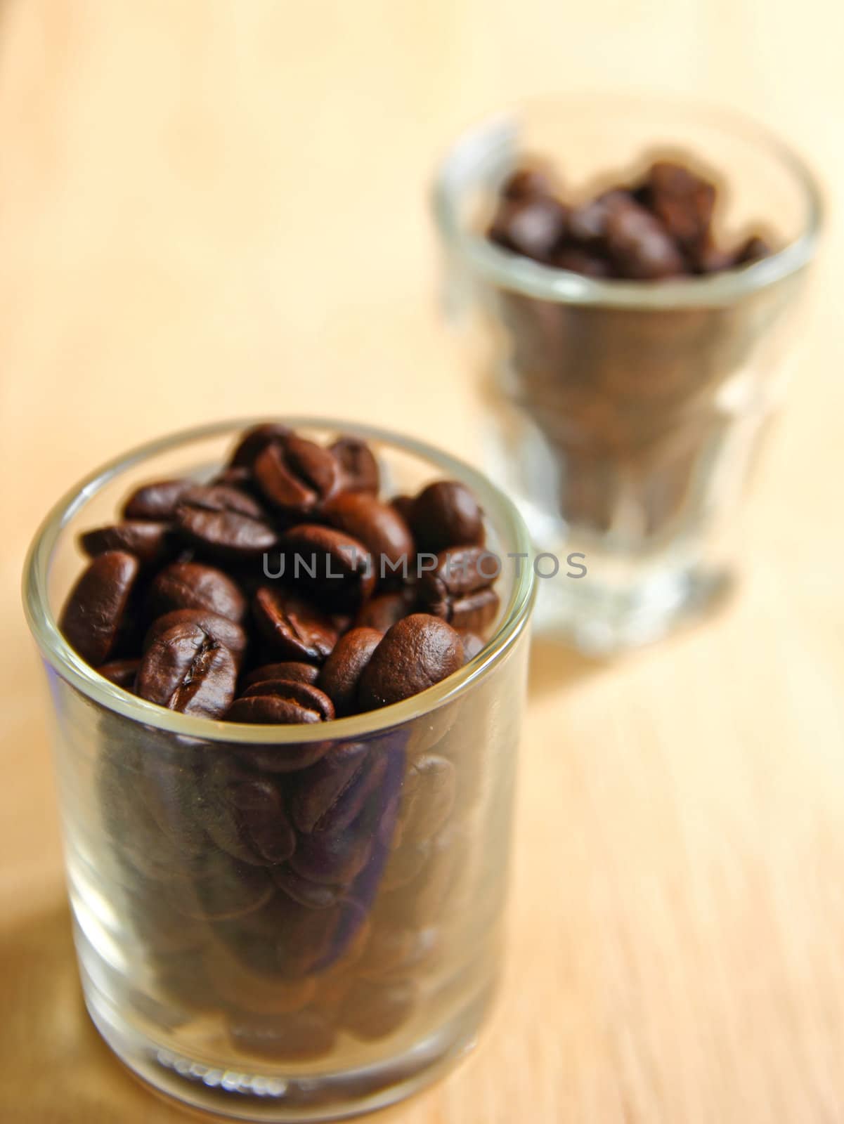 Coffee beans in glasses on wooden background