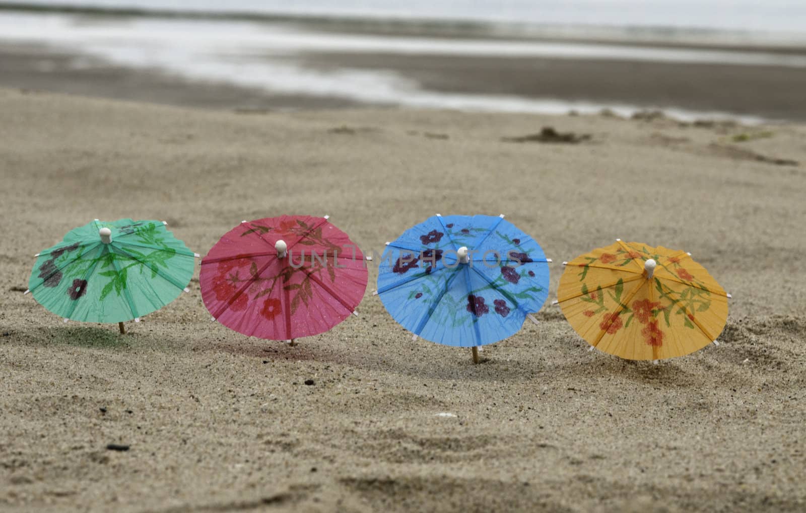 four parasol on the beach in green purple yellow and blue