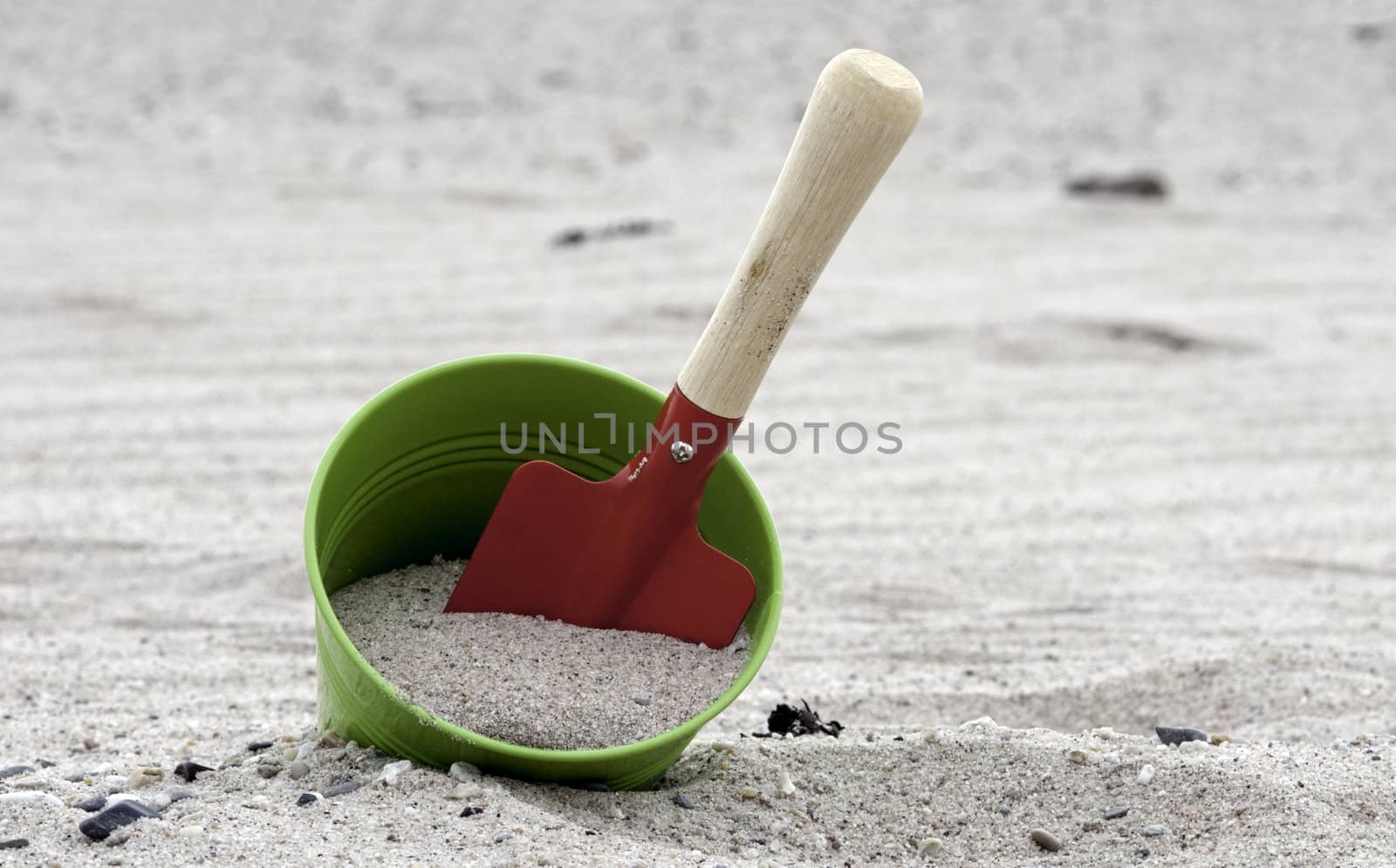 red and green shovel and bucket on the beach