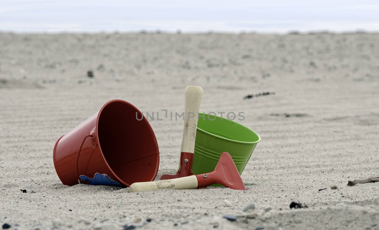 red and green shovel and bucket on the beach