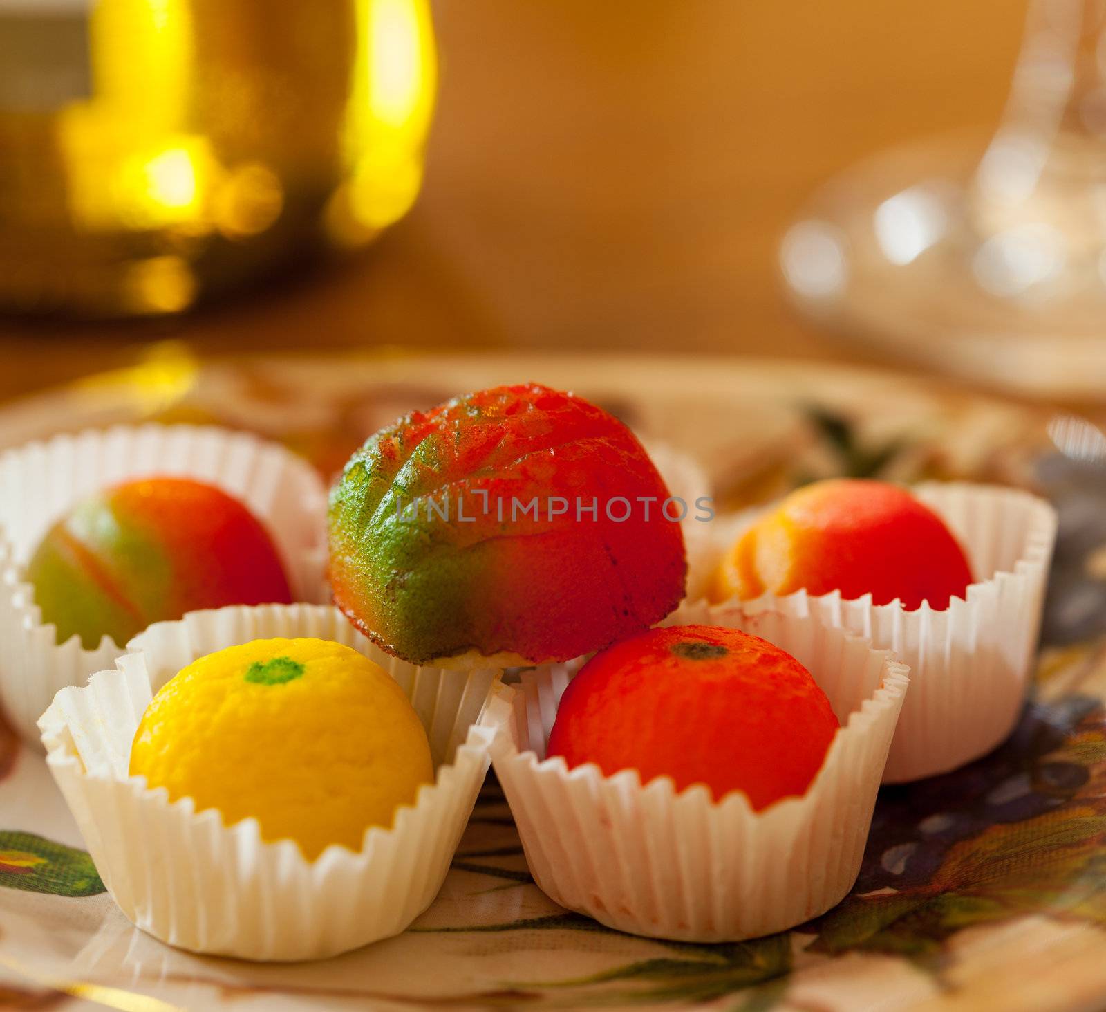 Fruit shaped candies in macro image of marzipan sweets on table with glass and bottle of wine