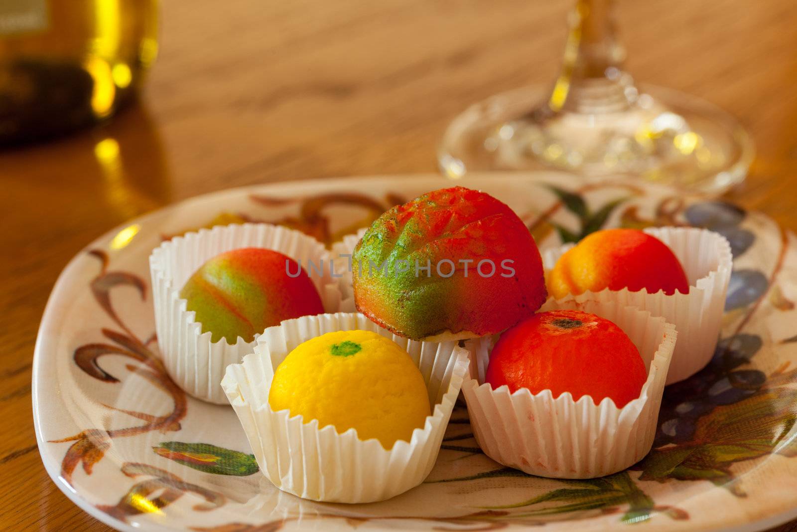 Fruit shaped candies in macro image of marzipan sweets on table with glass and bottle of wine