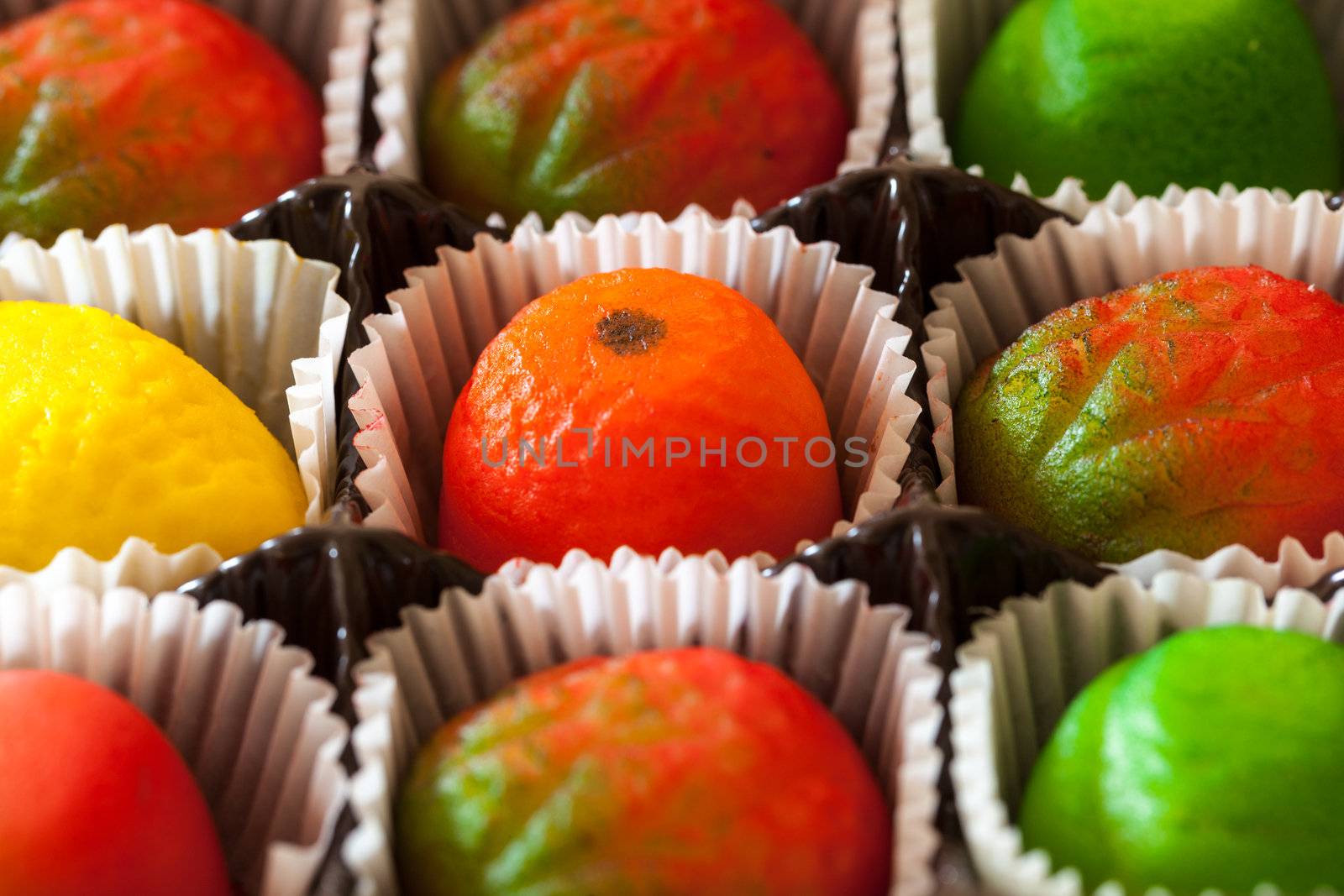 Fruit shaped candies in macro image of marzipan sweets in paper wrappings