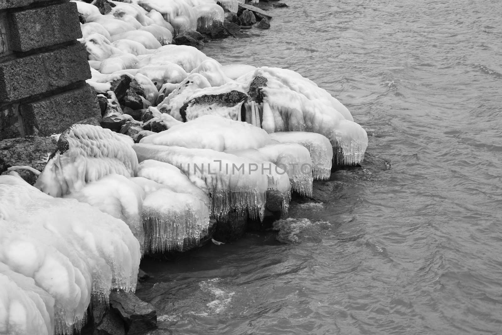Heavy winter weather deposits ice on rocks on the water's edge