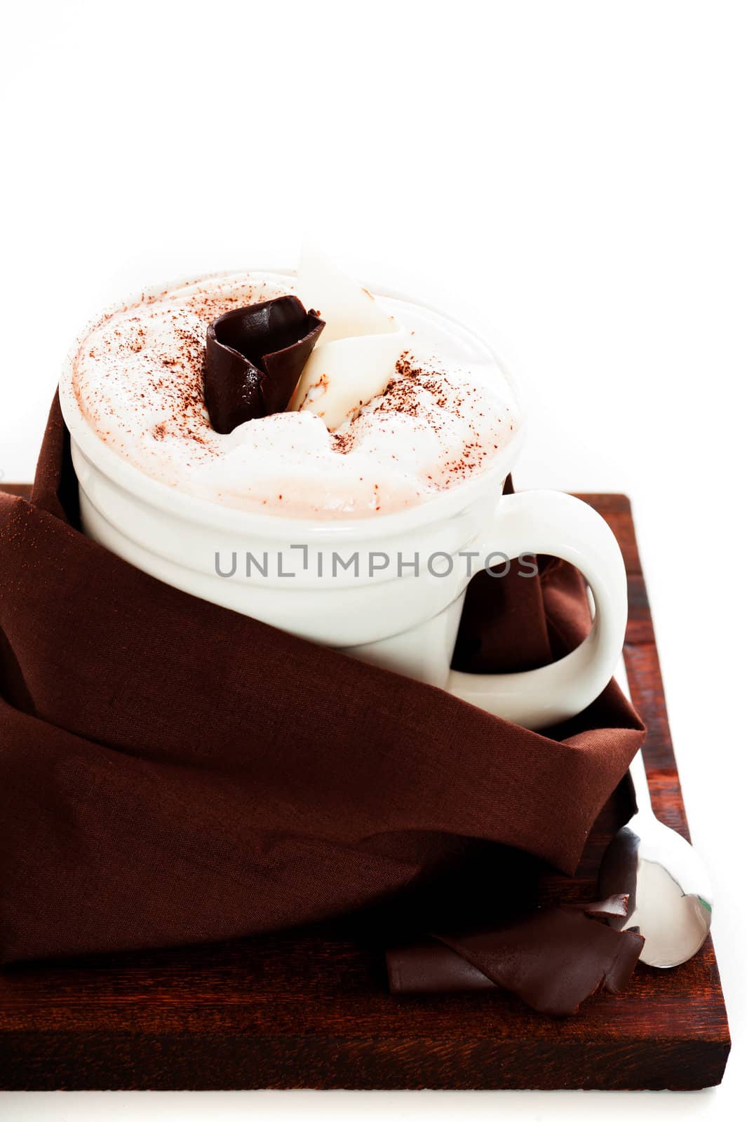 A cup of chocolate or cappuccino with brown napkin on a dark wooden board, spoon and twisted chocolate as decoration
