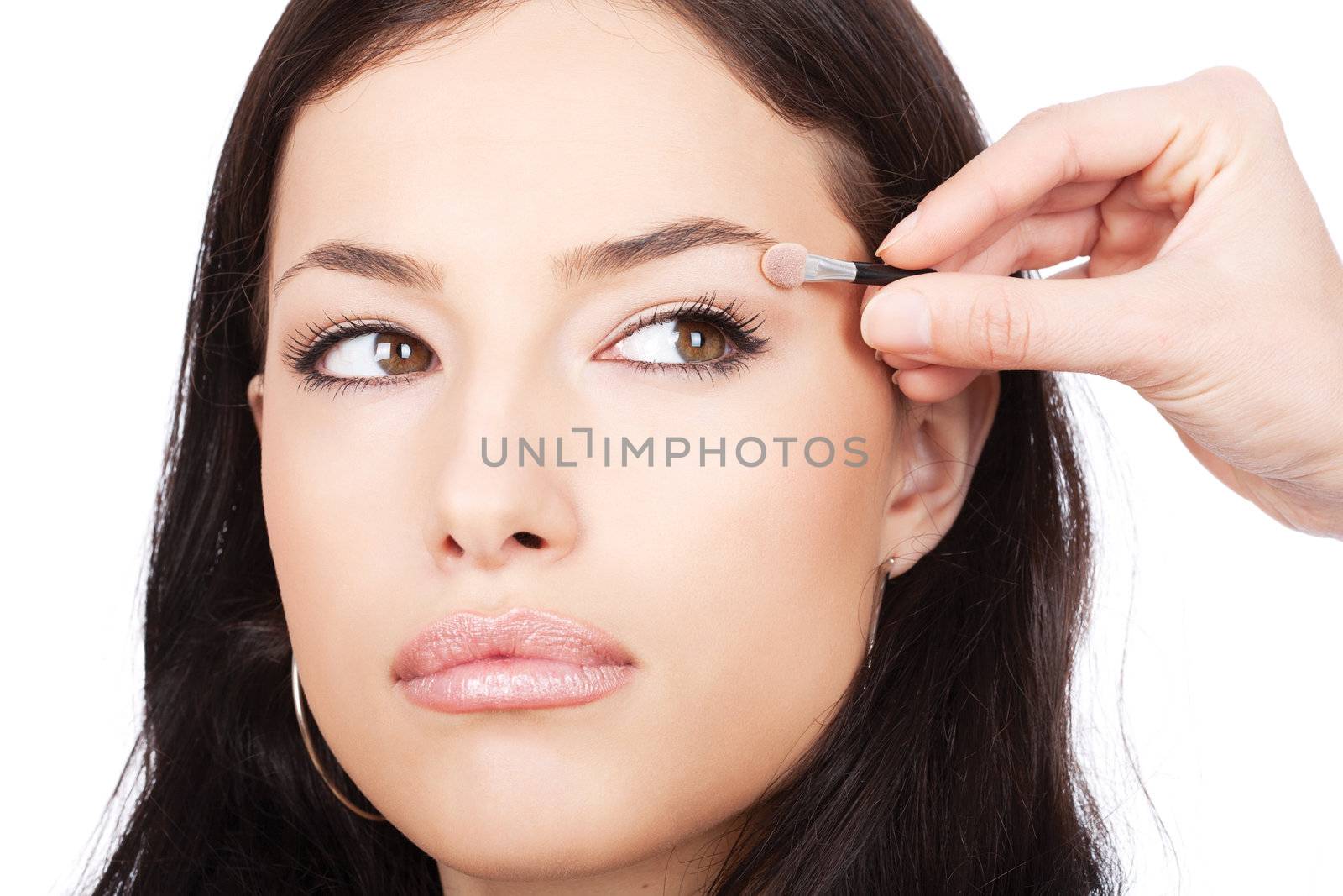 Model receives eyeshadow from make-up artist, isolated on white background