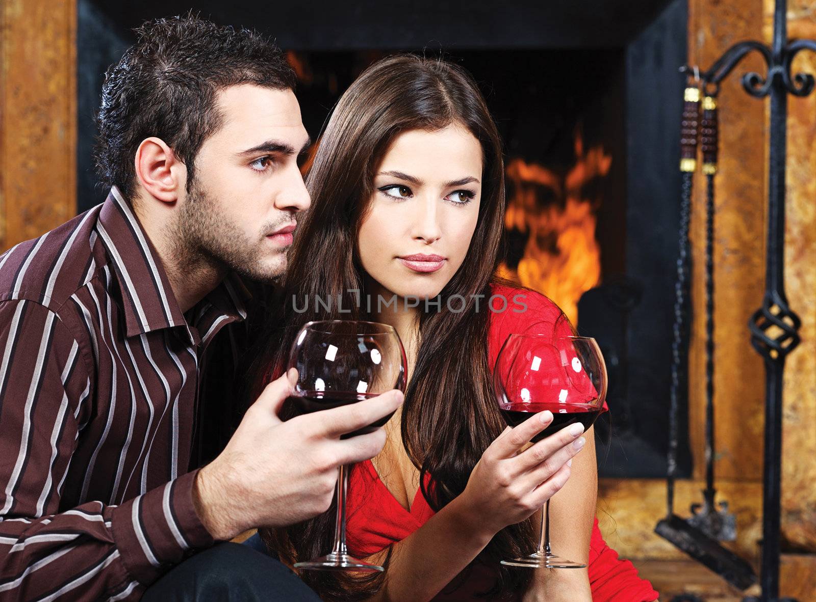 Romantic couple near fireplace drinking red wine by imarin