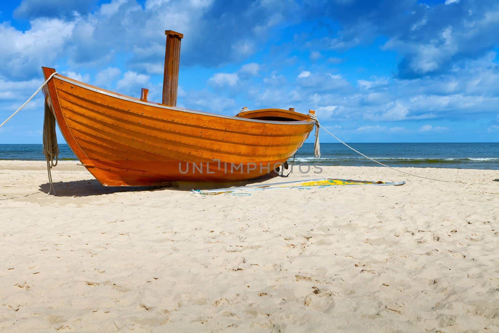 Wooden fishing boat on a sandy beach in sunny day