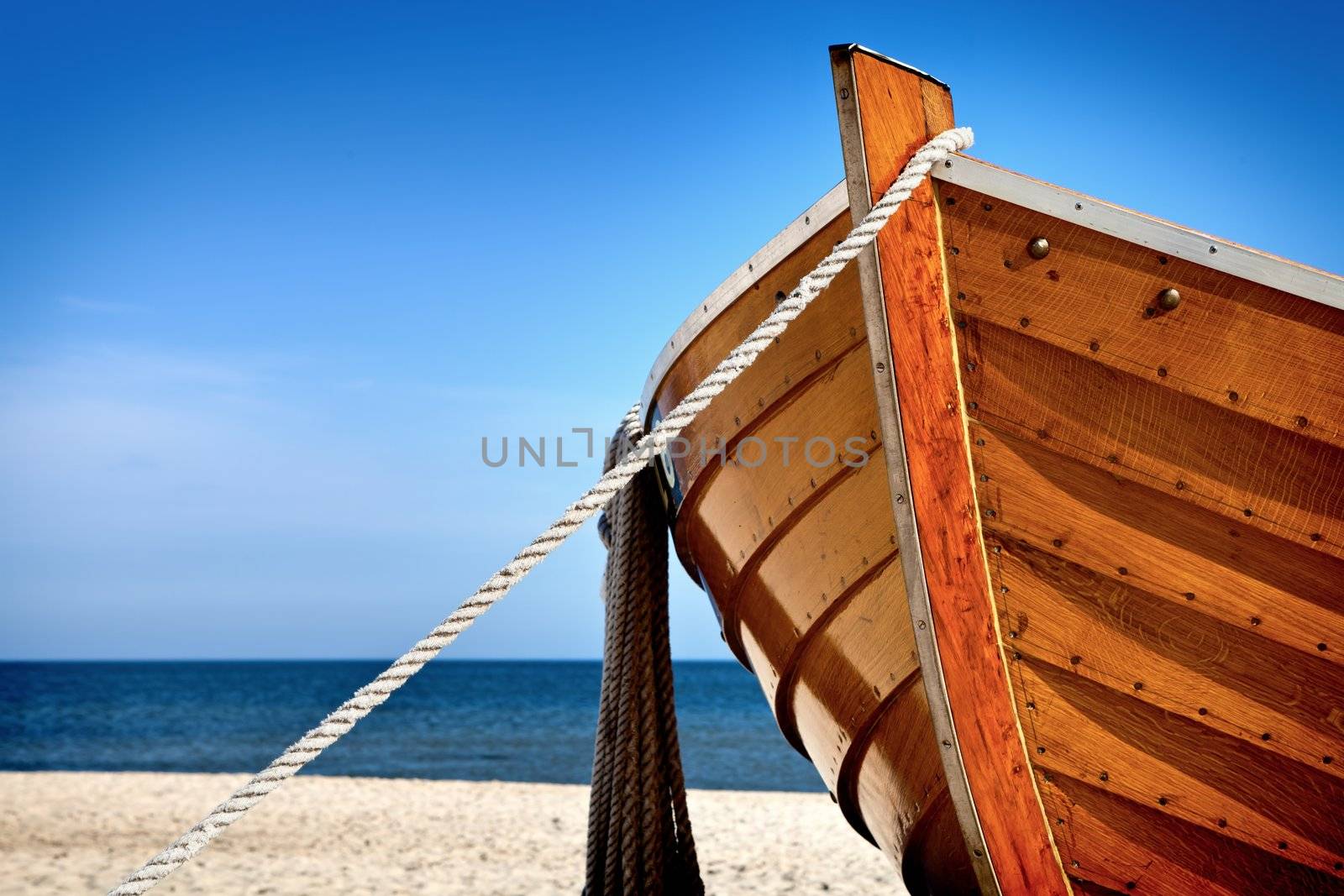 Front view of a wooden fishing boat, sea in background and blue sky with copyspace