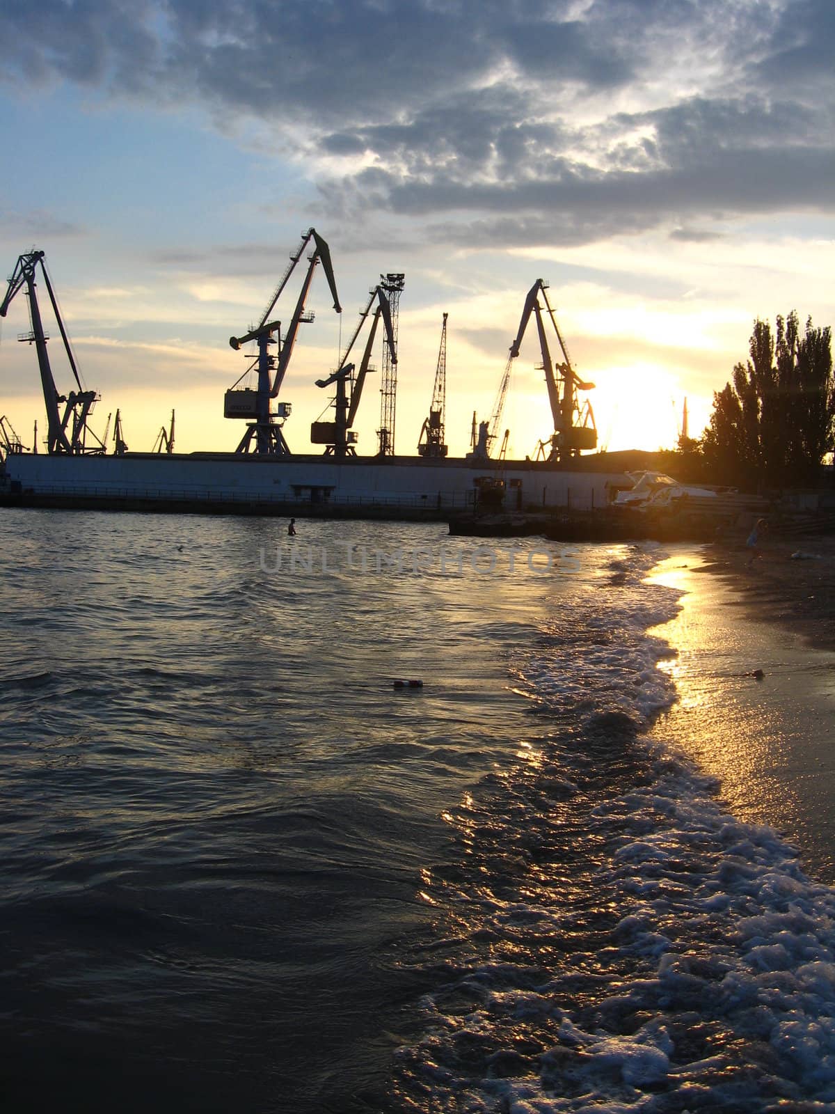 everning sea with hoisting crane in the seaport by alexmak