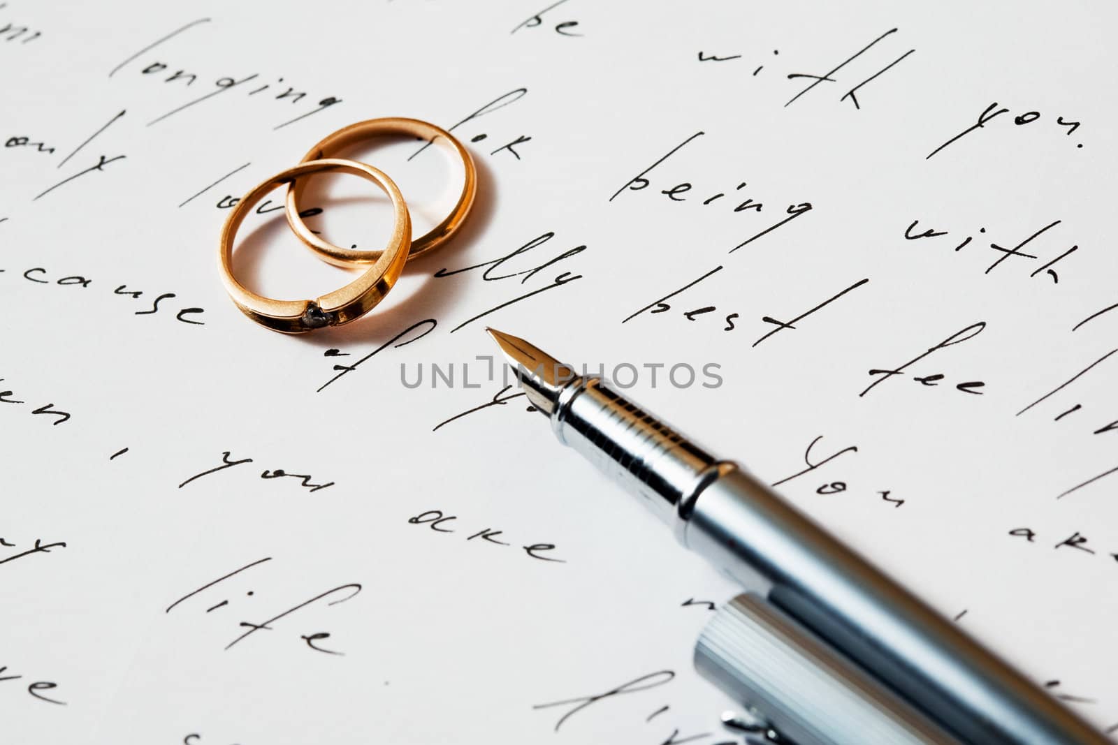 An image of two rings and a pen on a letter