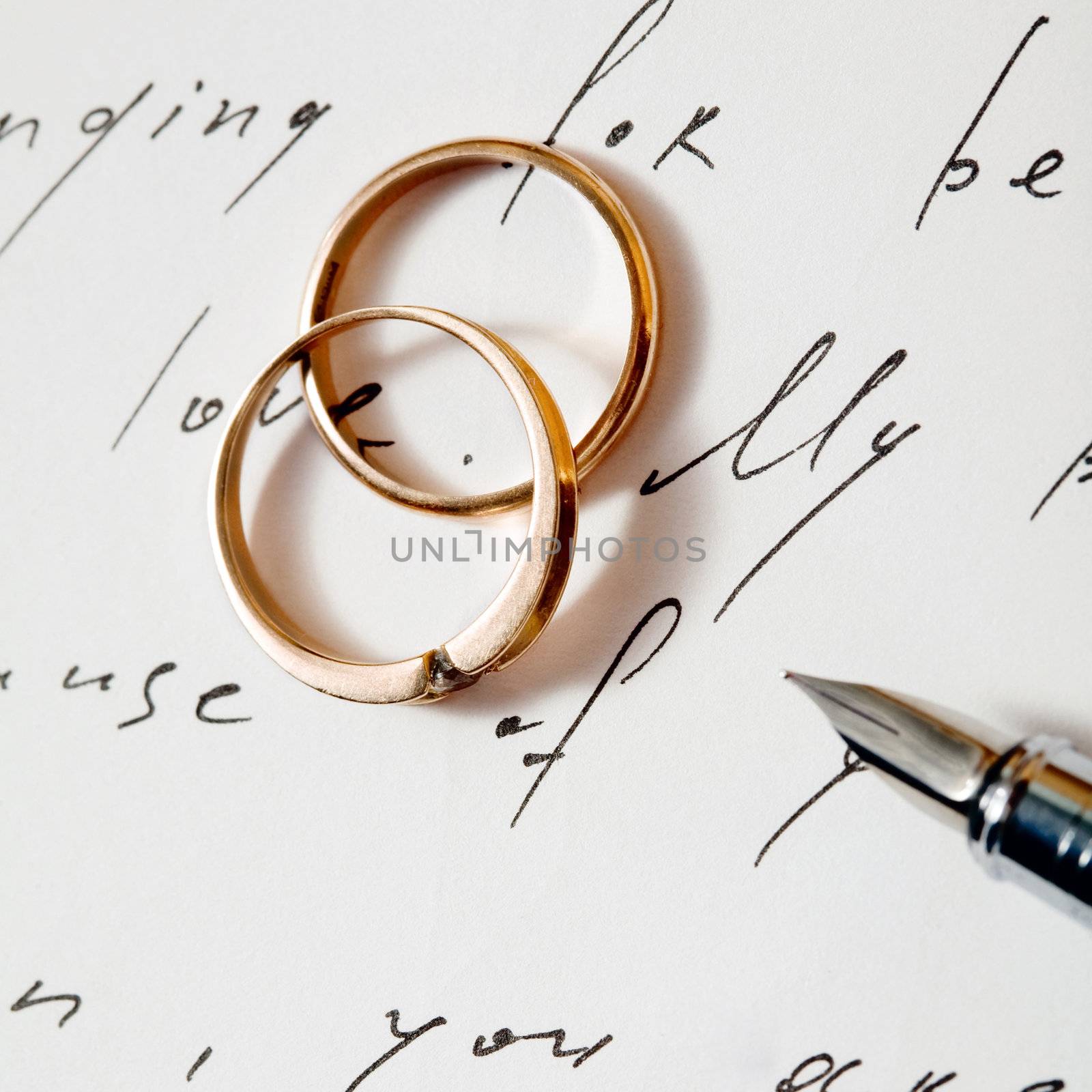 An image of two wedding rings on a letter and a pen