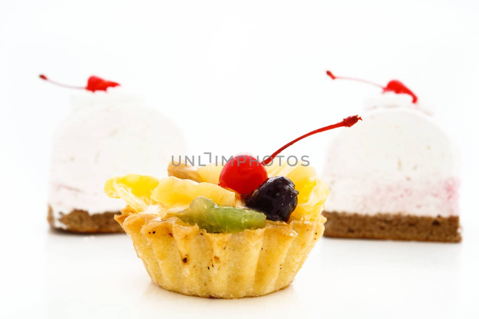 An image of cakes with cherry on top. On white background.