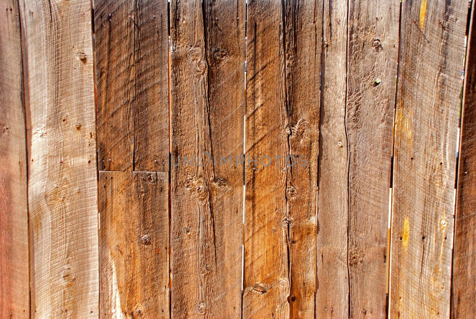 An old wooden fence with lots of grain and knots, put together with rusty nails