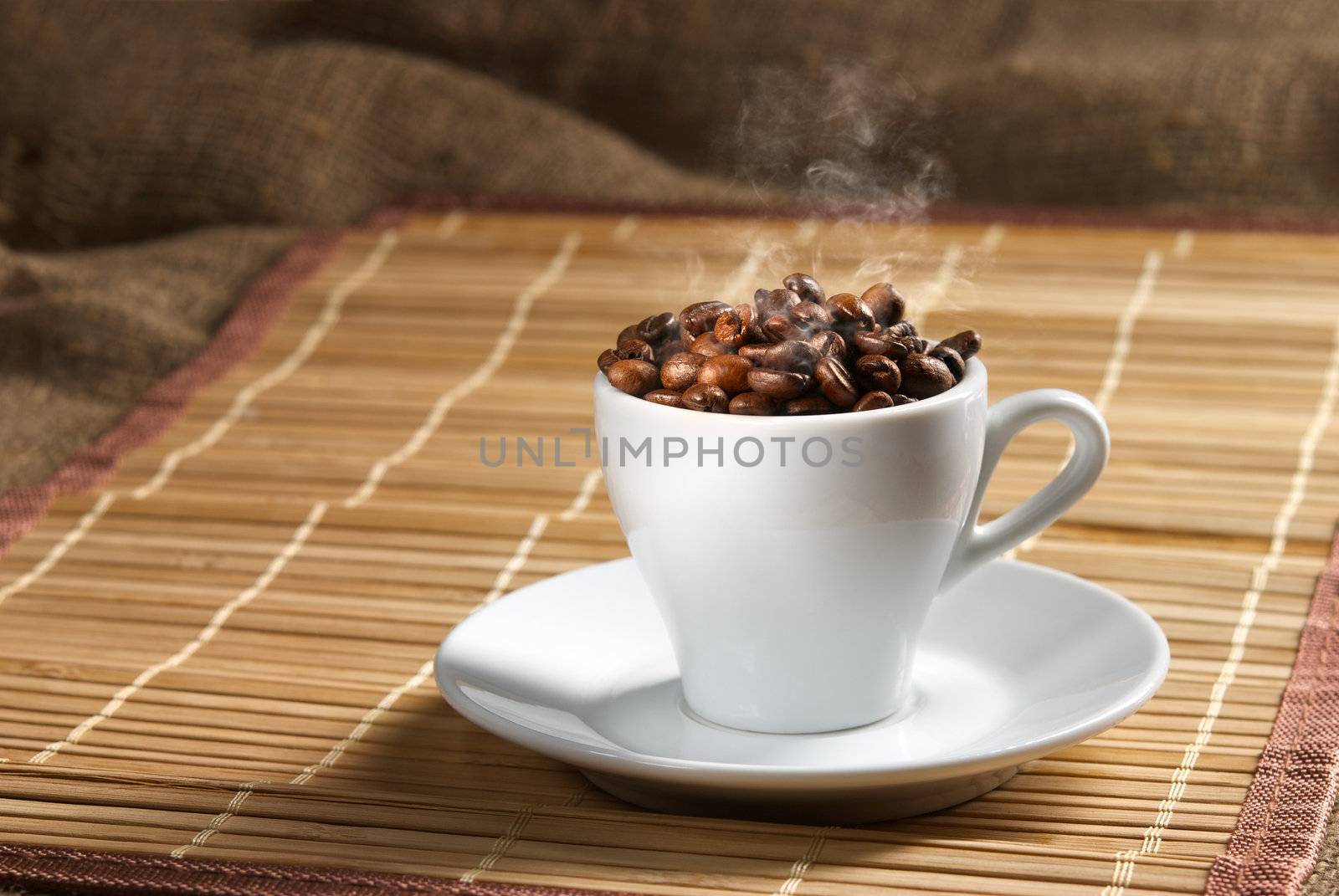 Still life with white coffee cup full of coffee beans