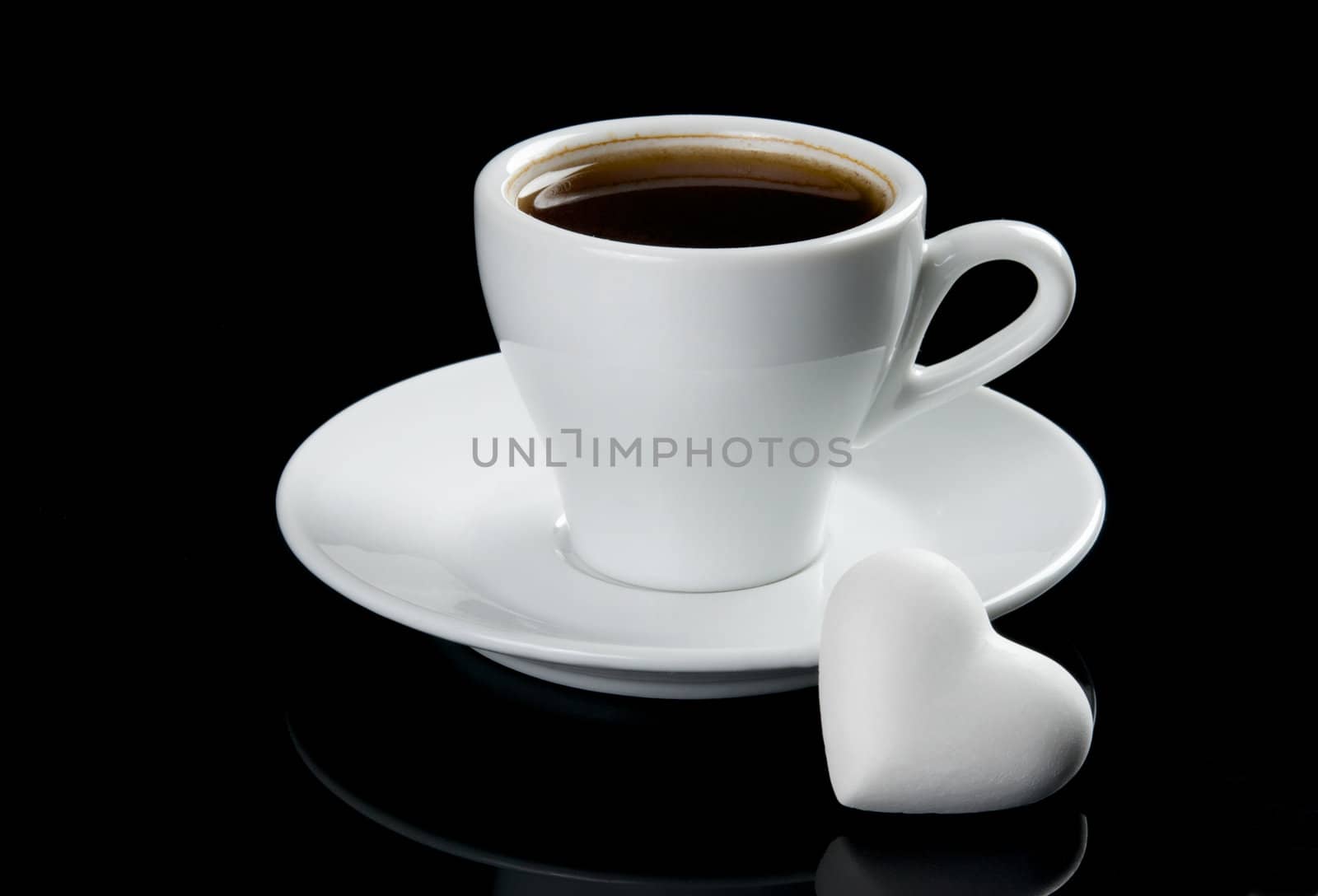 Cup of coffee with heart shape cookie. Isolated on black background