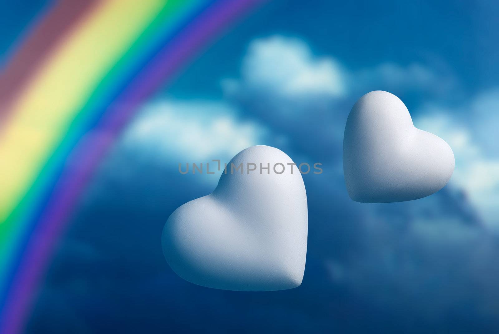 Rainbow and two hearts against a blue sky background