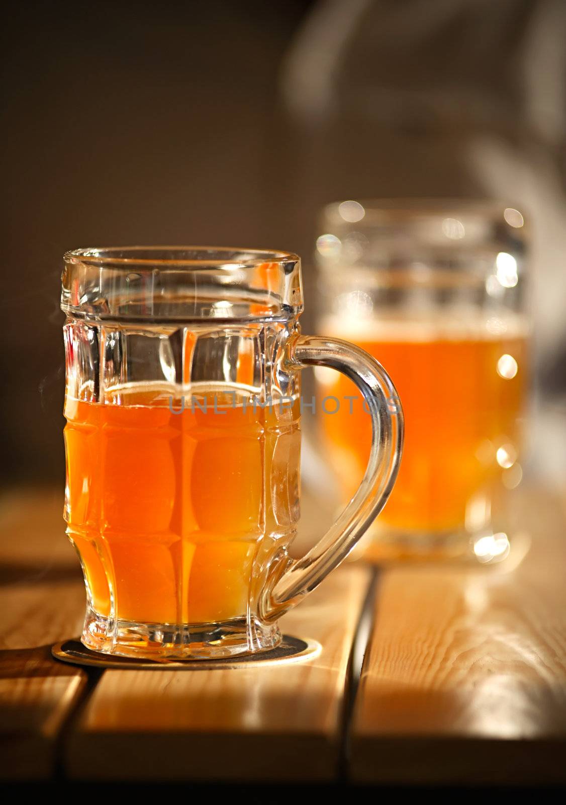 Two beer mugs close-up on wooden table. Small depth of field