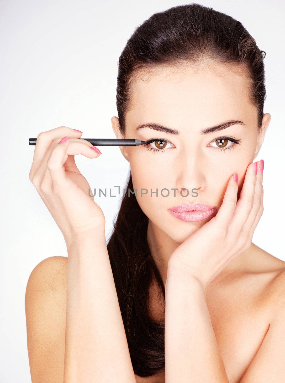 woman applying cosmetic pencil on eye by imarin