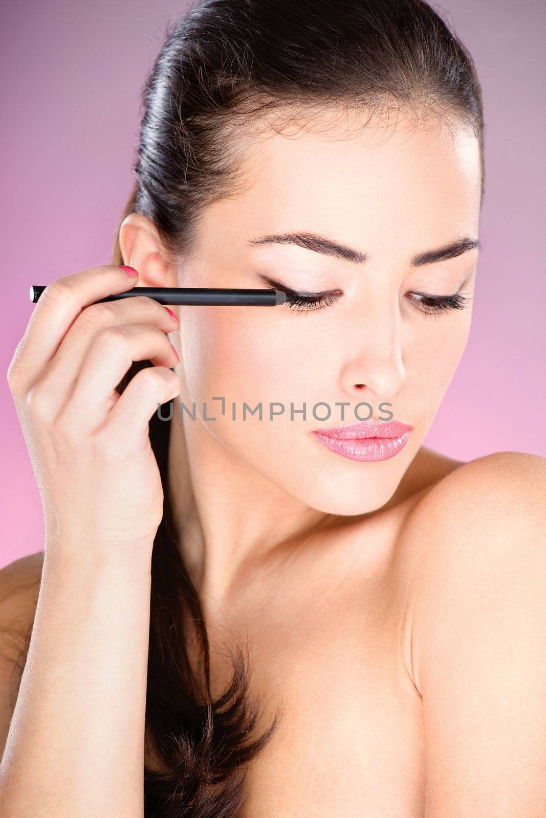 pretty woman applying cosmetic pencil on eye